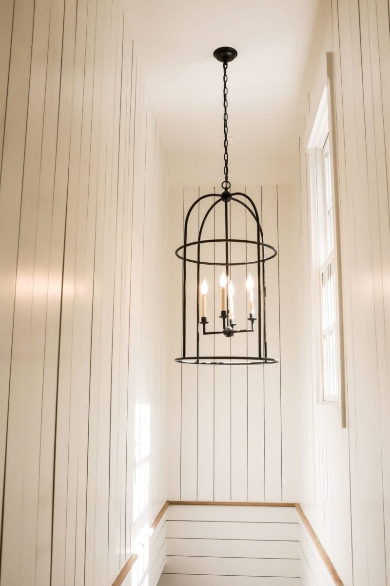 Shiplap clad stairwell with round, iron foyer light