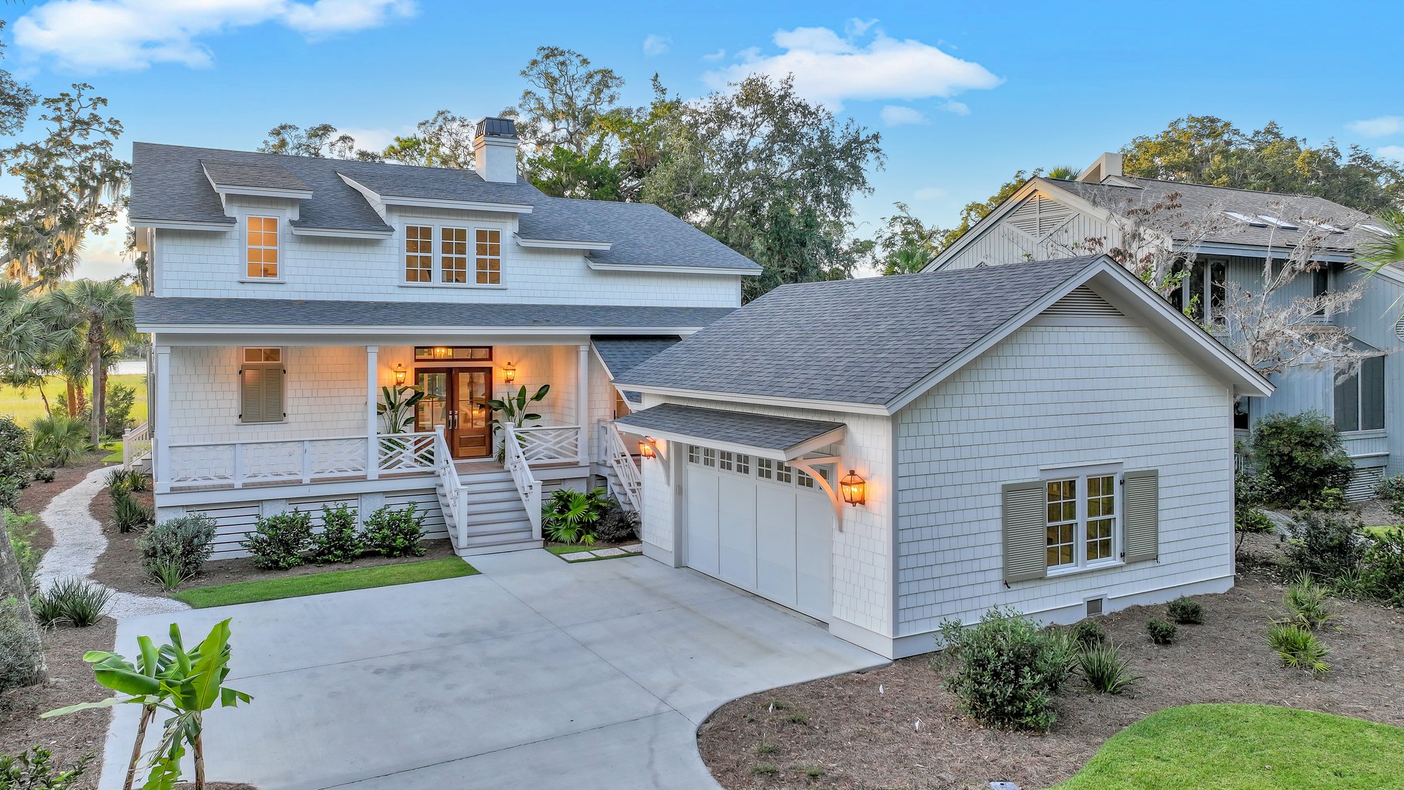 Southern Cottage with detached garage with light gray shake-style siding, front porch, and wood door