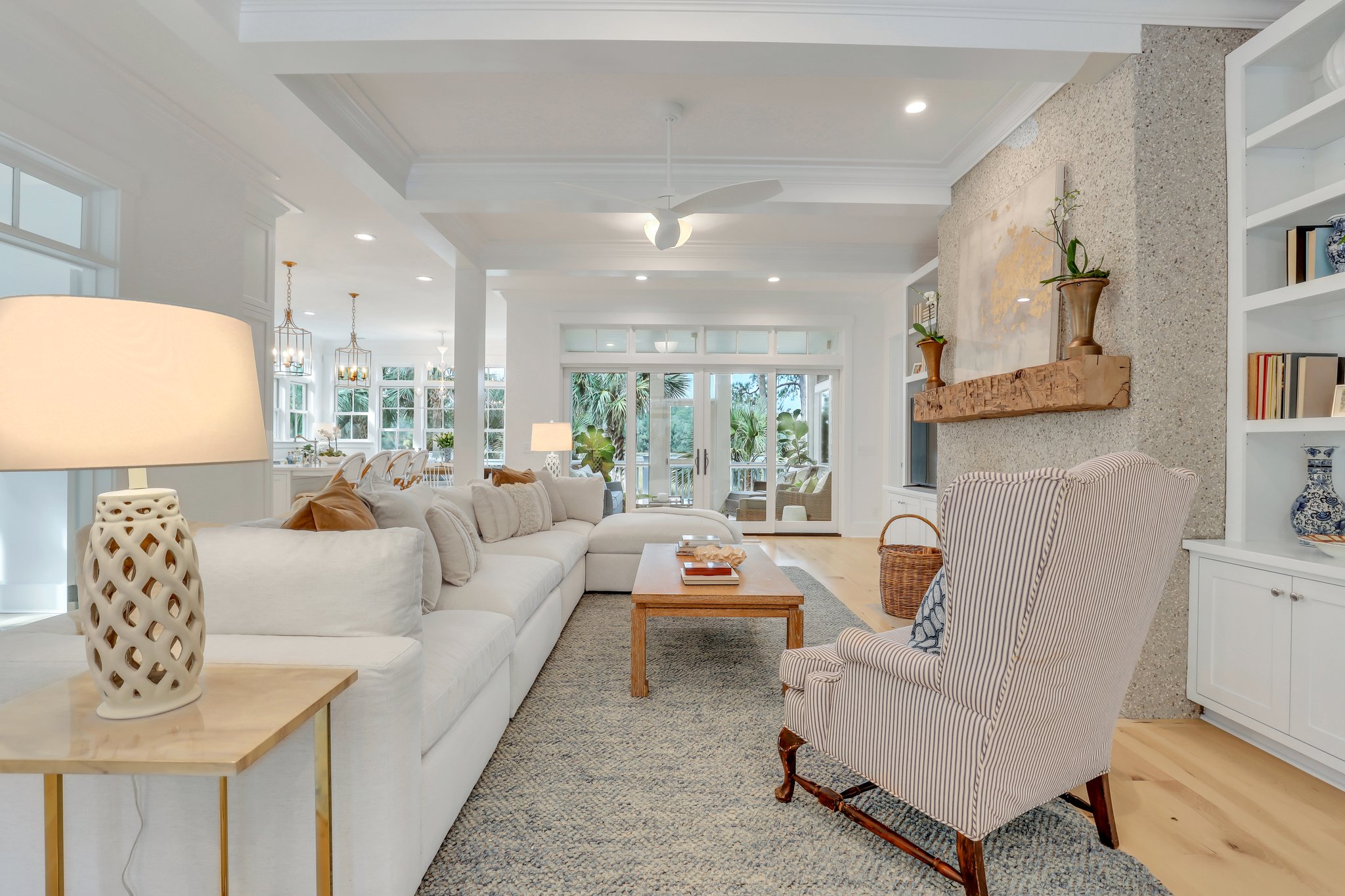 Peaceful and coastal inspired living room with tabby fireplace with natural mantle and flanking built-ins, along with coffered ceiling.