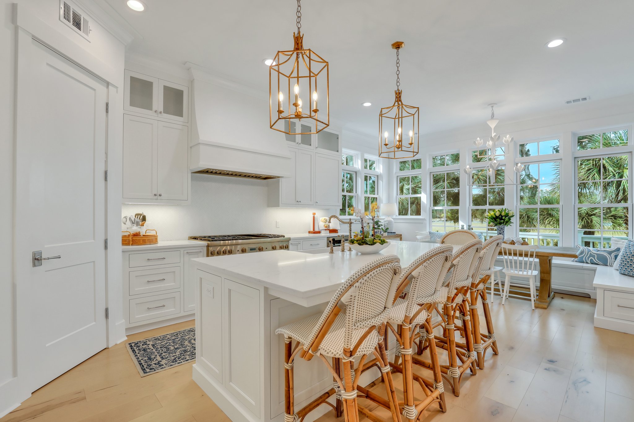 Bright white chef's kitchen in coastal style cottage home on the coast of Georgia with river and marsh views. Center island, custom cabinet vent hood