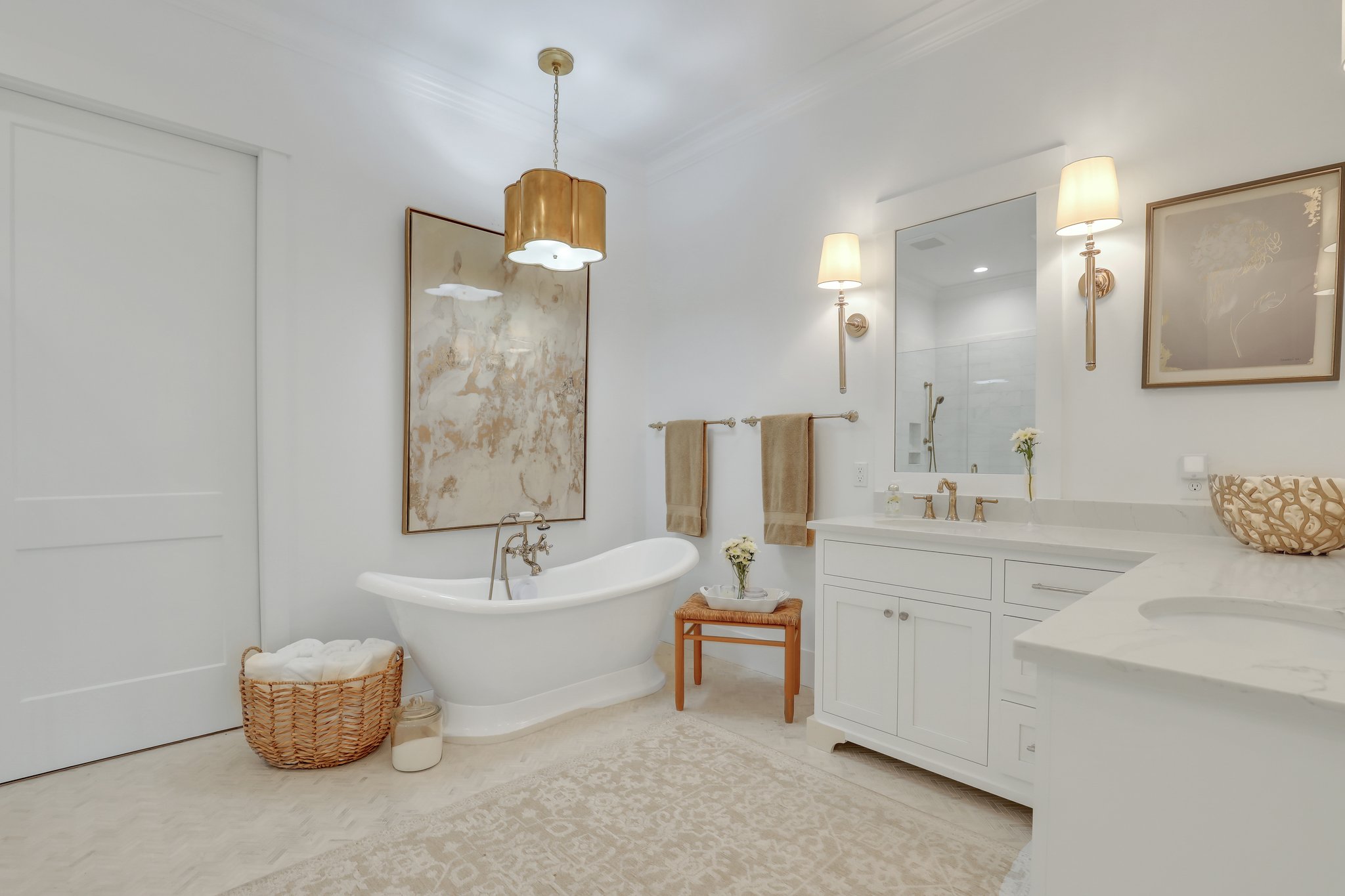 Master suite bathroom with gold accents, free standing tub, white cabinetry, and access to closet